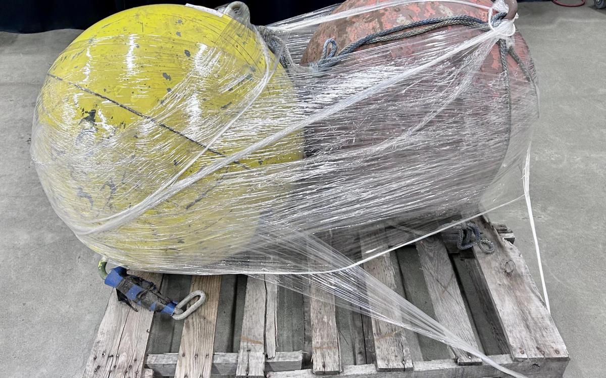 Two round metal buoys on a pallet.
