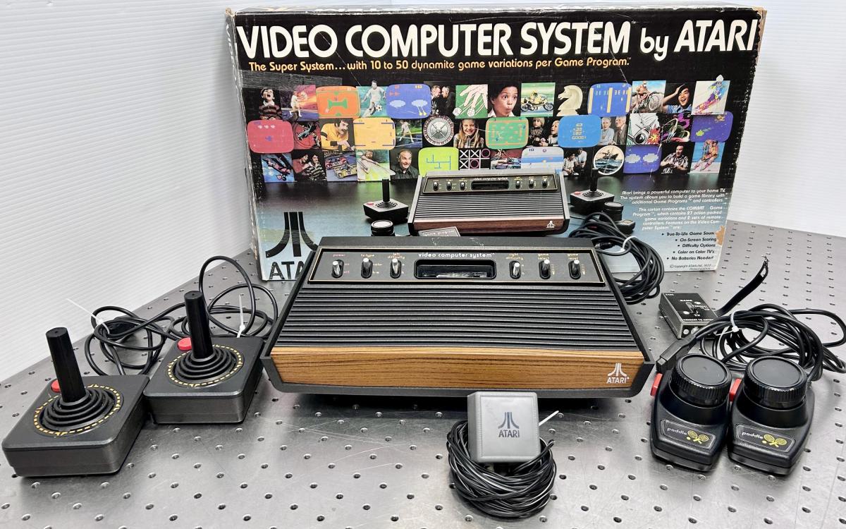 Atari video game system with controllers and original box shown behind it.