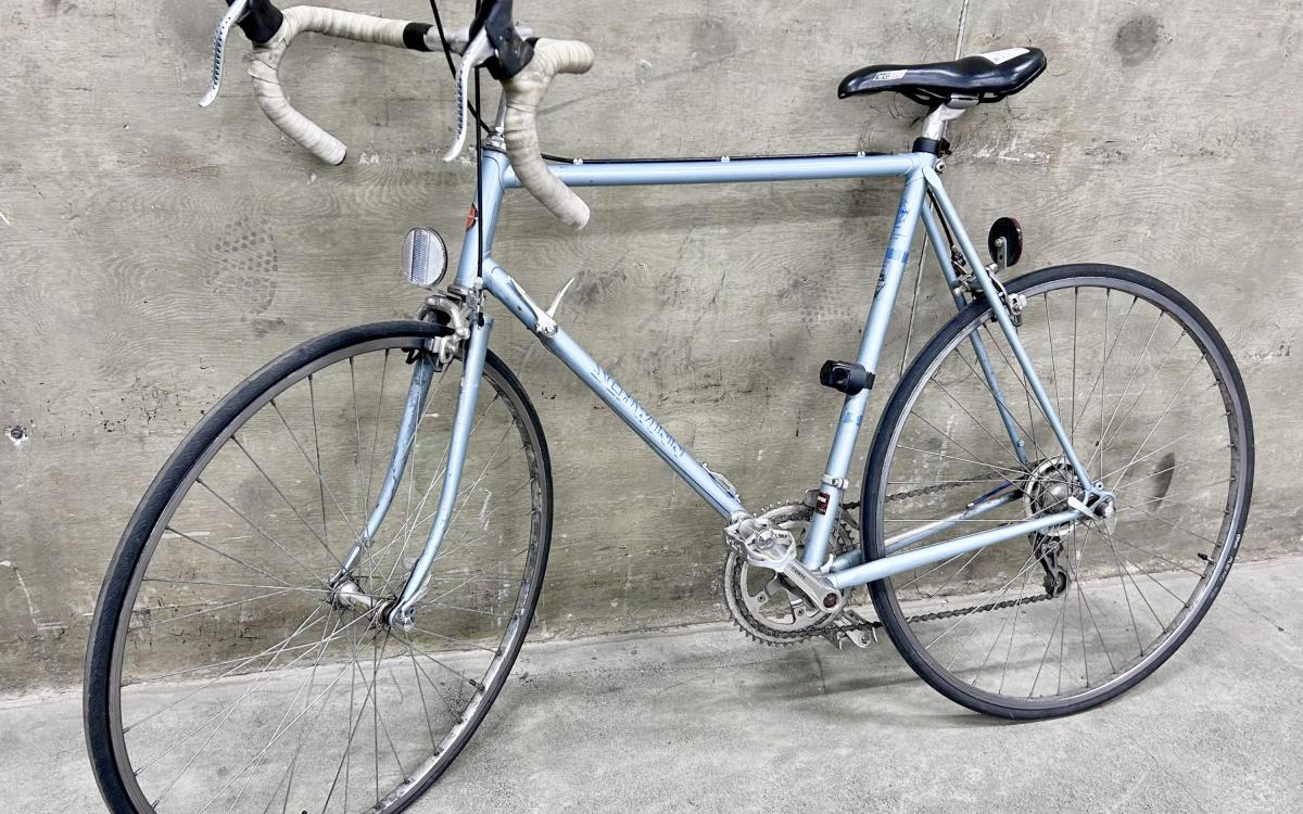 Silver blue vintage road bike against a cement wall.