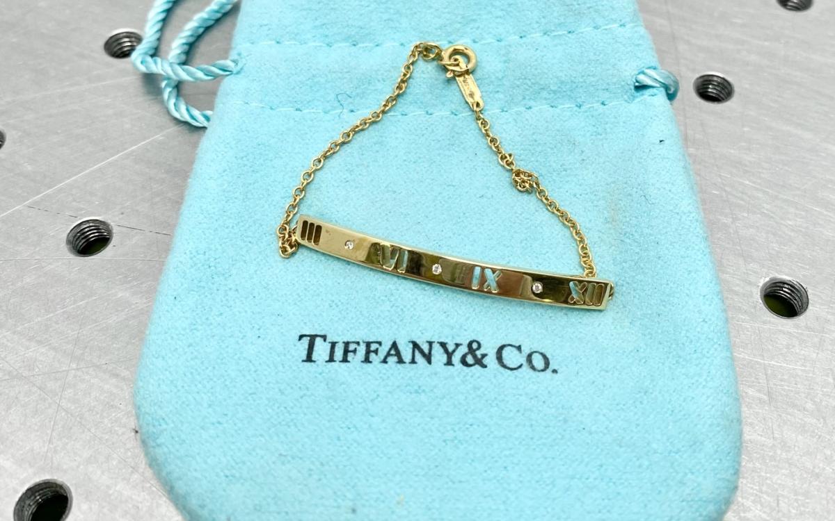 Gold bracelet sits on a Tiffany & Co pouch.