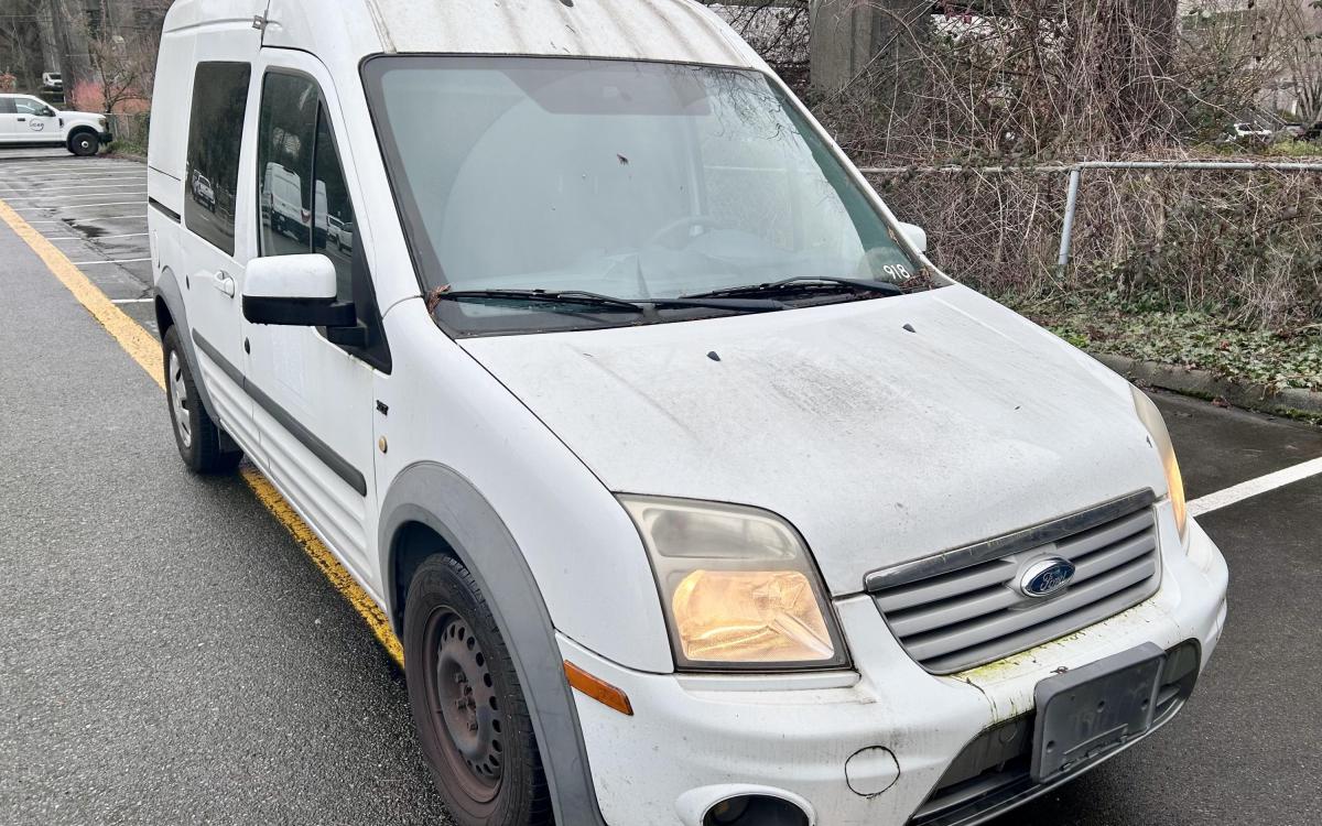 White Ford Transit Connect van in a parking lot.