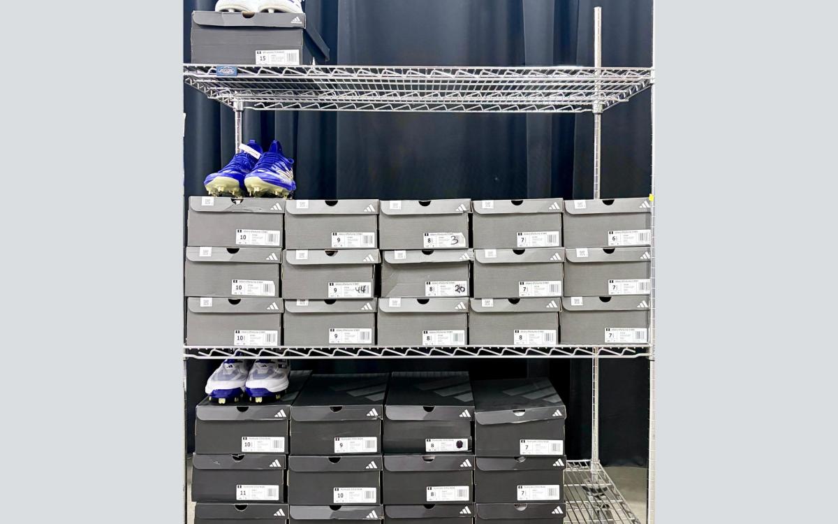 Rack full of 28 pairs of Adidas show boxes with three pairs of cleats visible.