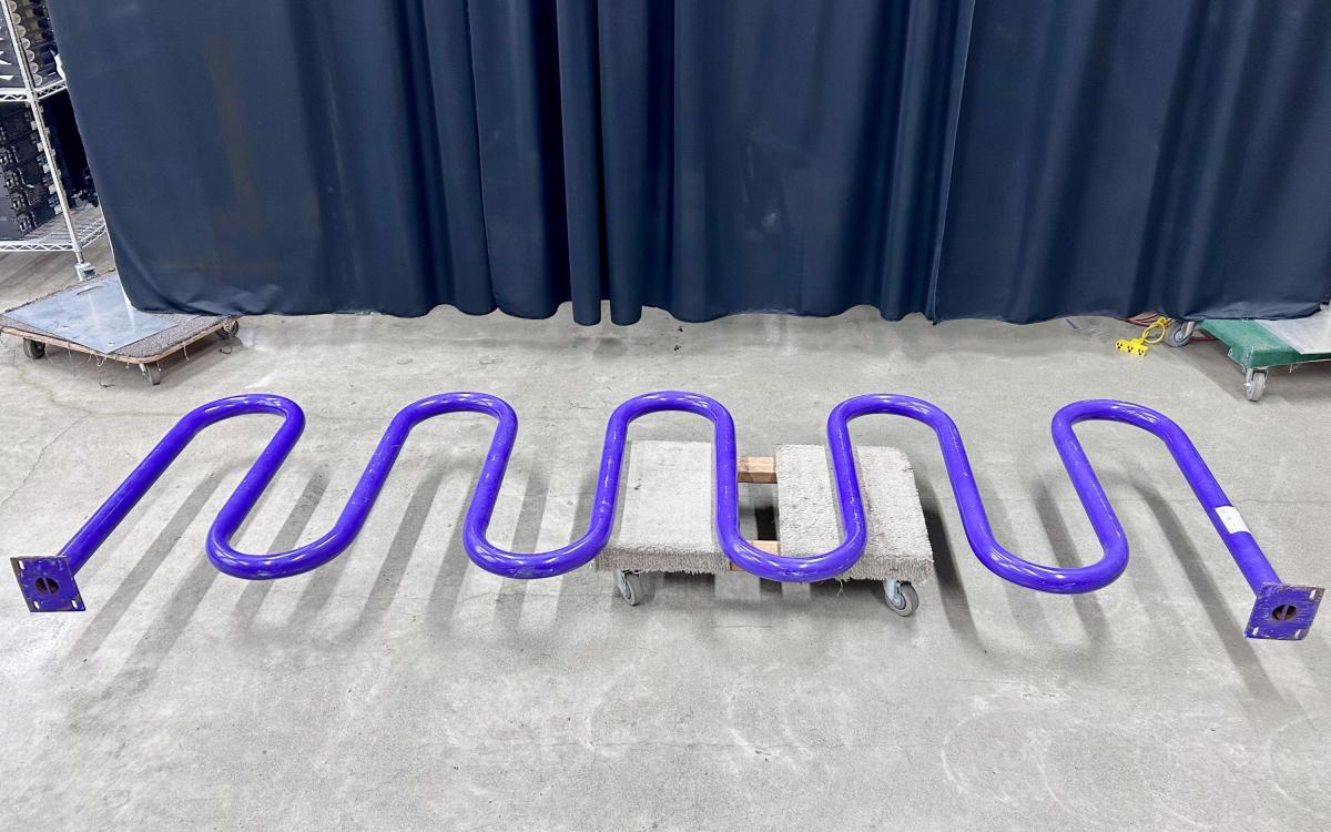 Purple bike rack sideways on a moving dolly.