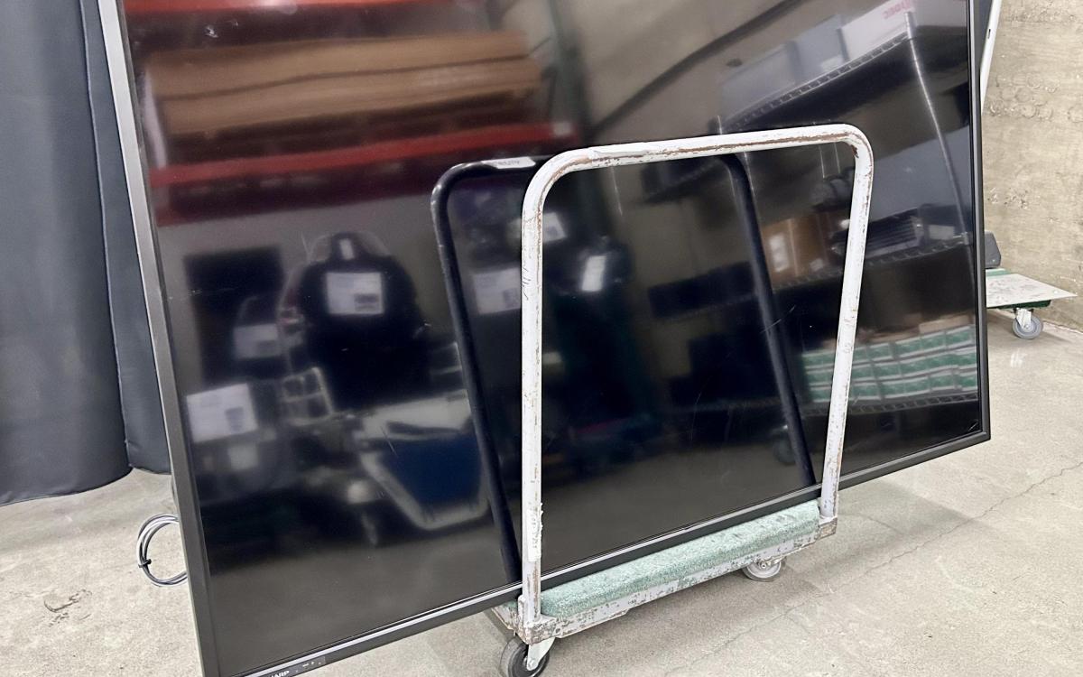 Large shiny black monitor on a moving cart.