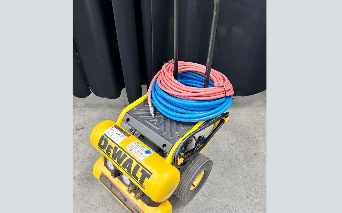 Yellow DeWalt compressor on wheeled cart with hoses.