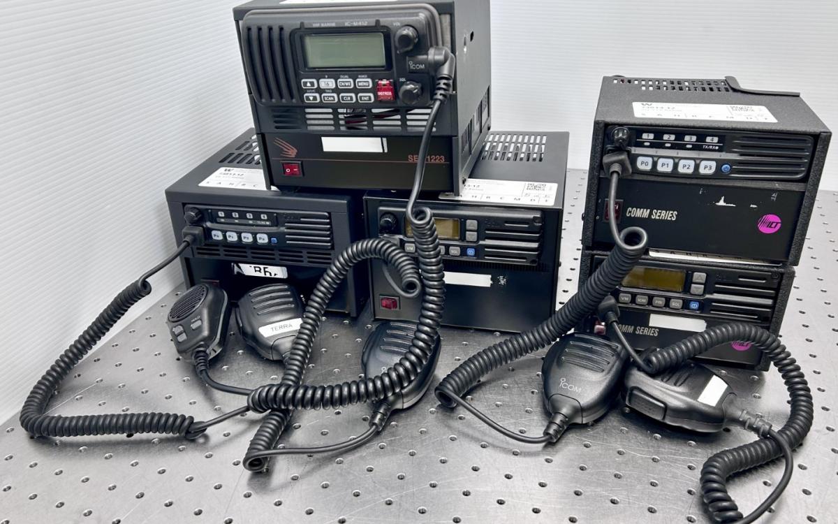 Five black mobile radios with attached microphones.