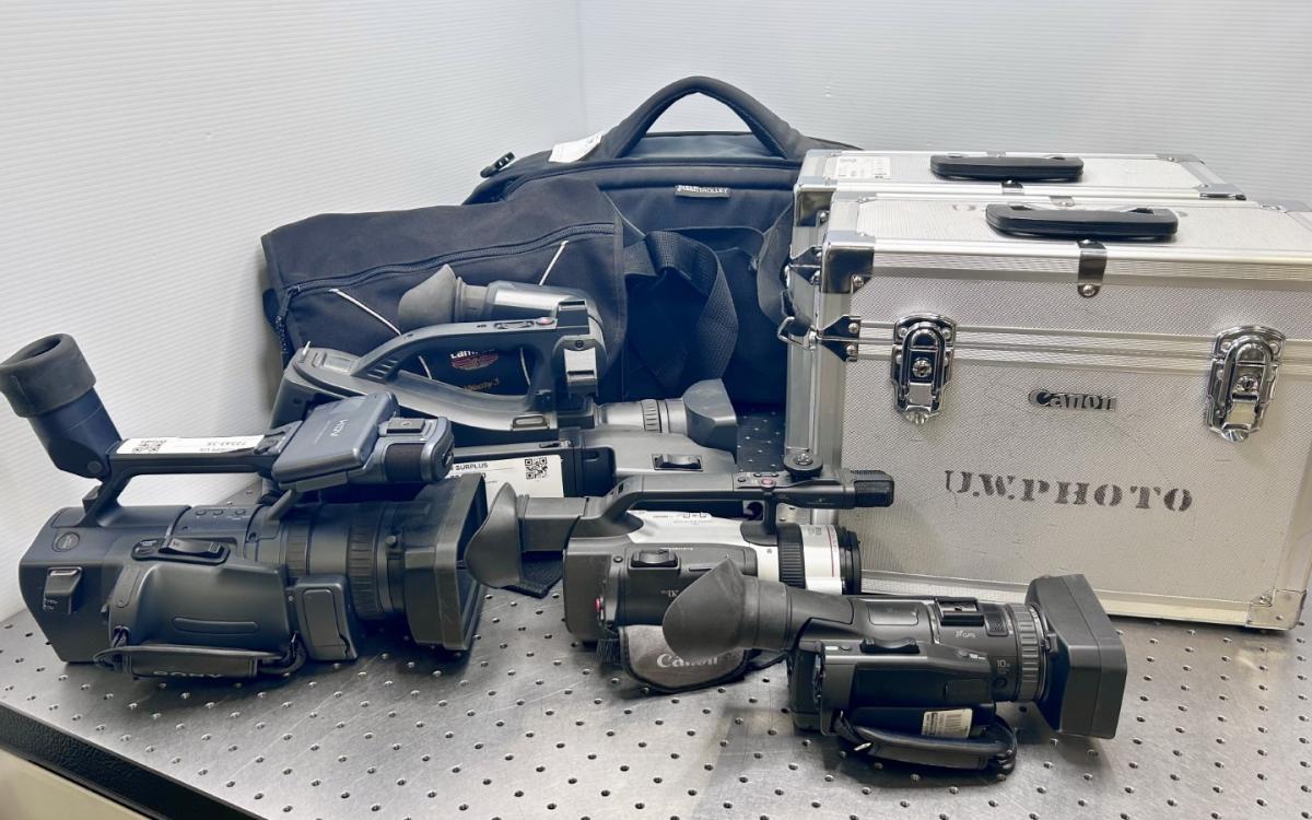Video cameras, some in cases, on a table.