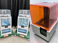 Stitched photo of two matching 3D printers, and one different one.