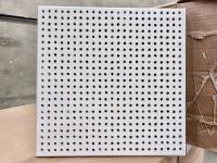 A sample perforated acoustical tile sits on boxes. 