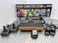 Atari video game system with controllers and original box shown behind it.
