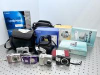 Various digital cameras displayed on a table.