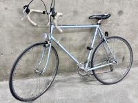 Silver blue vintage road bike against a cement wall.