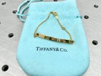 Gold bracelet sits on a Tiffany & Co pouch.