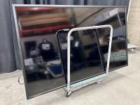 Large shiny black monitor on a moving cart.