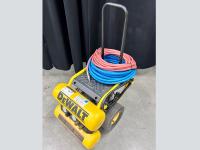 Yellow DeWalt compressor on wheeled cart with hoses.