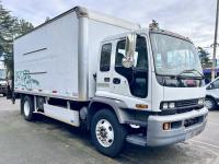 White GMC box truck with graffiti on side in a parking lot.